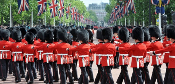 tourism-business A wide shot of The Royal Guard marching under a row of British flags.