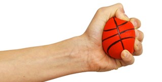 Under pressure at work A hand squeezes a stress ball that looks like a basketball.