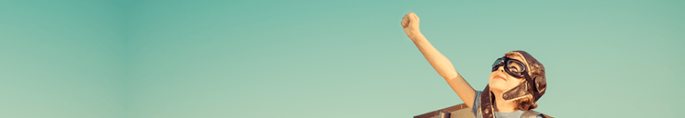 Great email siagnture.fw A child wearing a flying hat and goggles makes a fist and looks up at the sky.