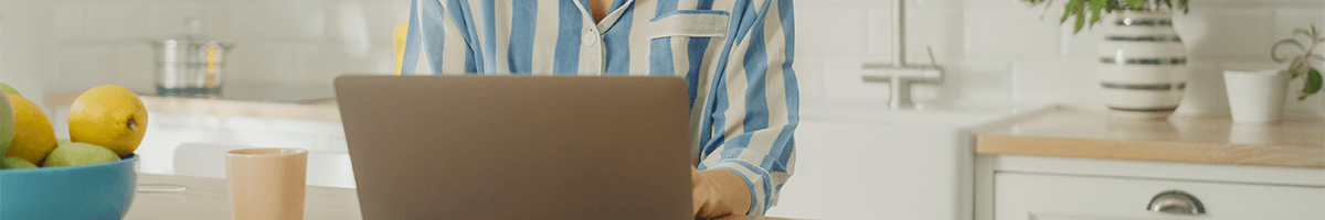 Musings from a remote-working Rocketseed newbie A woman sits behind a laptop in a striped blue shirt with a kitchen in the background.