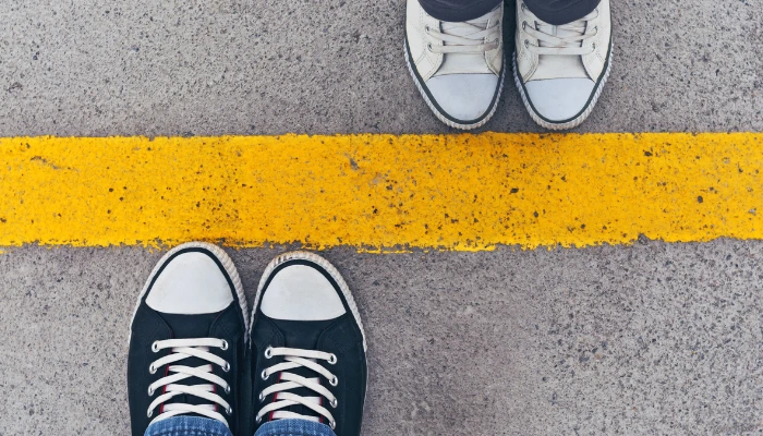 What every company needs to know about ATL, BTL, and TTL marketing in 2025 13 Top view of two pairs of sneakers standing on opposite sides of a yellow dividing line