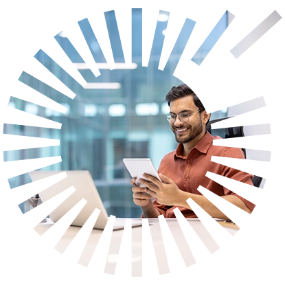 On-Prem Email Signature Management - Rocketseed A smiling man with glasses sitting at his desk behind his laptop working on his tablet
